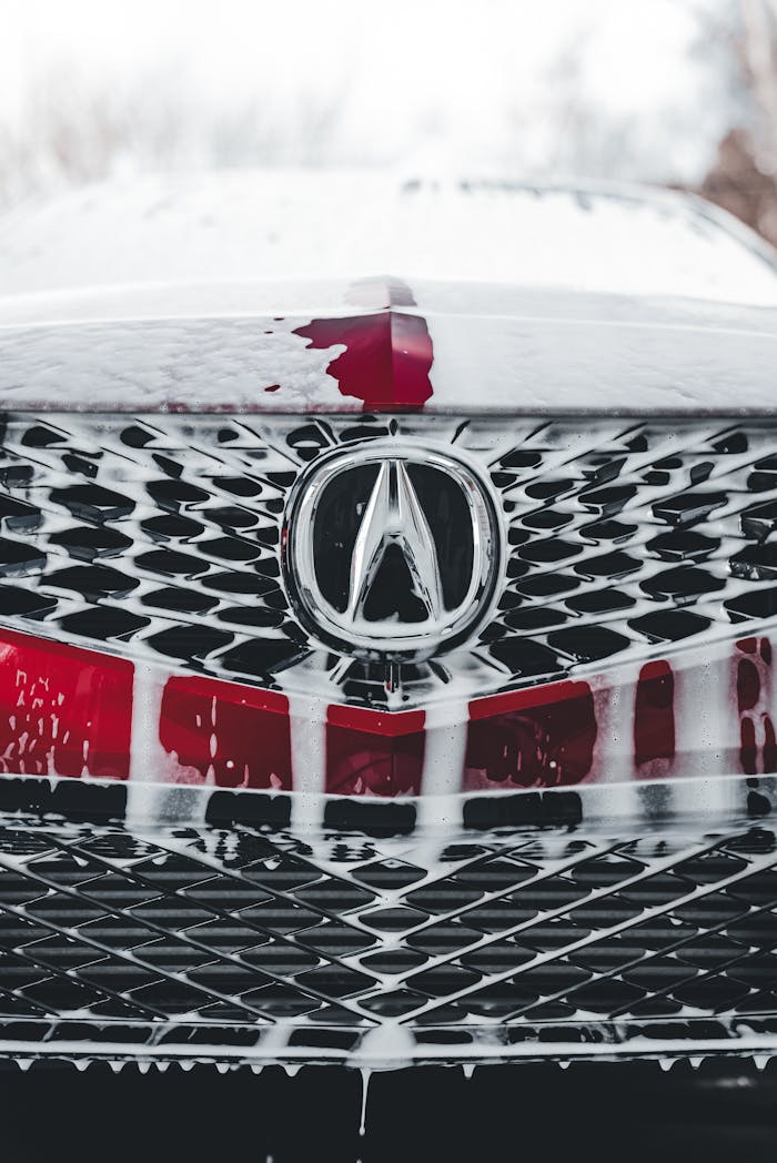 services-02 Detailed view of an Acura grille with soap suds during a car wash.