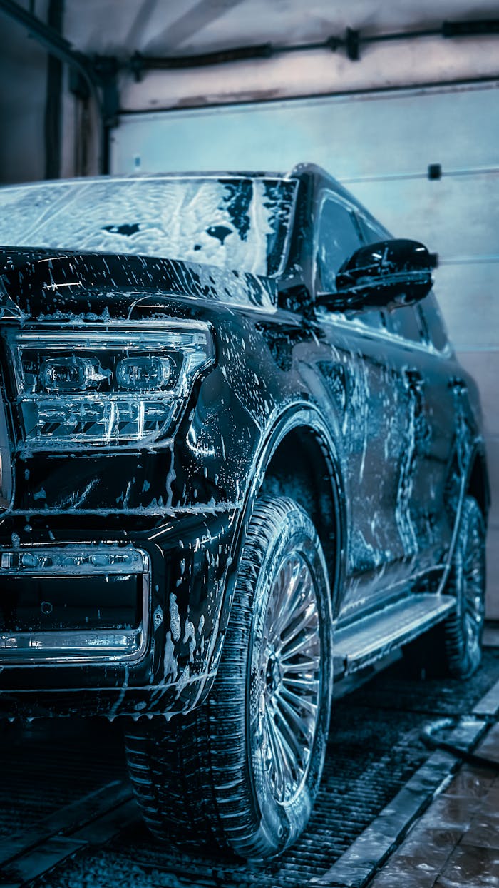 about-us-01 Close-up of a sleek SUV covered in soap during a car wash, highlighting cleanliness and care.