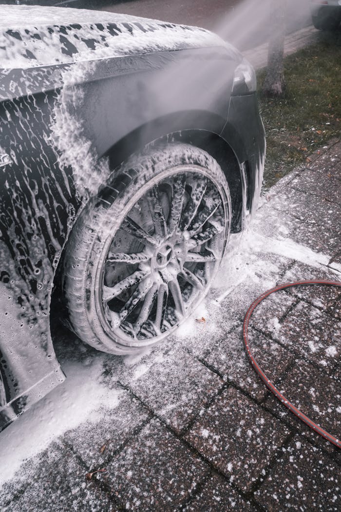 about-us-02 Close-up of a luxury car wheel being thoroughly washed with foam outdoors.